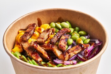 A vibrant poke bowl with grilled chicken, avocado, mango, edamame, red cabbage, and lettuce offers a healthy meal option.