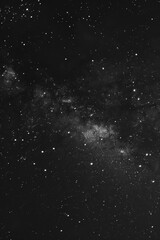 Fototapeta premium A black and white photo of a starry night sky. The stars are scattered throughout the image, creating a sense of depth and vastness. The photo evokes a feeling of wonder