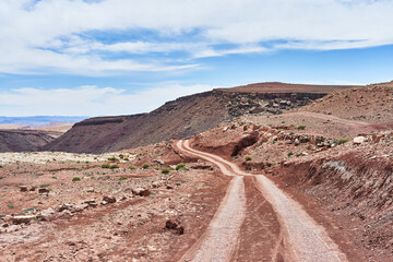A remote desert road meandering through a rugged barren landscape under a clear blue sky, devoid of people and vehicles.