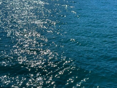 Blue sea glittering water with sun glare on surface