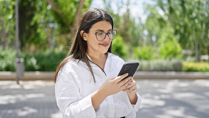 Young beautiful hispanic woman smiling happy using smartphone in the streets of Madrid