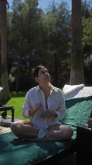 A contemplative young woman enjoys a peaceful moment with a cup of coffee outdoors at a bali resort.