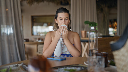 Young hispanic woman wiping mouth with napkin at the restaurant