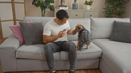 Young asian man playing with his dog in a cozy living room of an apartment.
