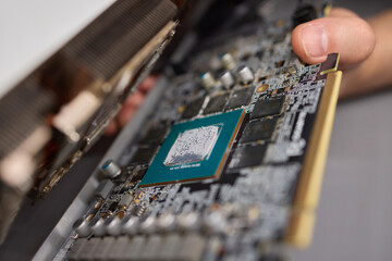 A technician is skillfully repairing a computer GPU fan with precision tools in a workshop