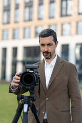 a photographer in a jacket with a camera on the background of a building.