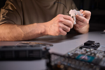 A technician is skillfully repairing a computer GPU fan with precision tools in a workshop