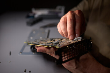 A technician is skillfully repairing a computer GPU fan with precision tools in a workshop