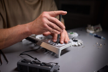 A technician is skillfully repairing a computer GPU fan with precision tools in a workshop