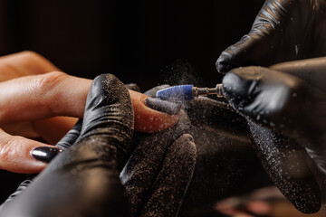 Manicurist doing hardware manicure to female client using special tools