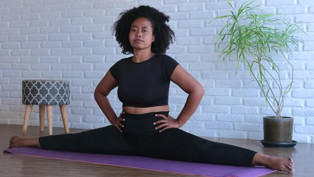 Athletic woman demonstrates stretching in splits on yoga mat. Deep stretching female improves flexibility and health body Regular stretching can help achieve impressive fitness results for flexibility
