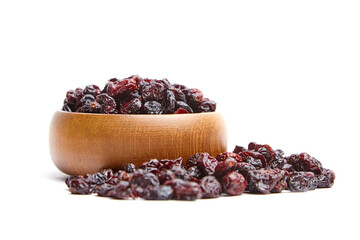 Wooden bowl filled with dried cranberries, with additional cranberries spilled in front, isolated on a white background. The rich red and dark hues highlight their wrinkled texture