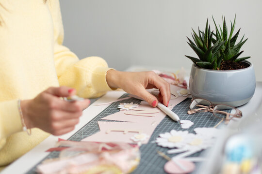 Unrecognizable young woman engaged in paper crafting at a desk