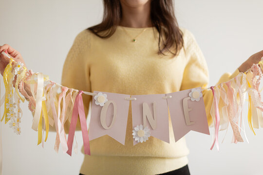 Unrecognizable young woman displays handmade party banner