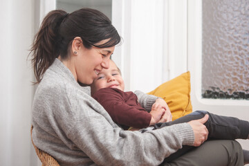 Mother and child sitting relaxed in an armchair with smiles on their faces. Concept of family, motherhood and children.