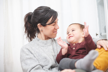 A look of complicity between mother and toddler as they relax in a living room armchair Motherhood concept.