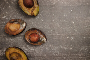 Chilean Hass Paltas, top view of four halved paltas in decomposition with mold, on a gray concrete...