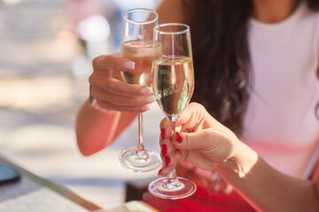 Two friends lifting cocktails in a lively bar scene, expressing joy and celebration