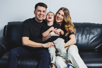 A happy married couple with a little son. Mom, dad and smiling son. Stylish family.