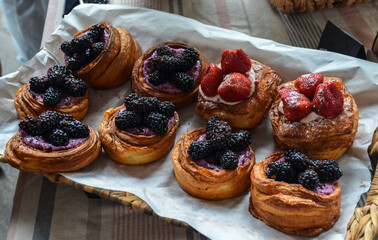 Assortment of freshly baked custard pastries with their golden-brown crusts adorned with cream and vibrant berries blackberries and strawberries 