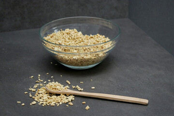 Top view of dried soy bean meat mince in a glass bowl with a wooden spoon, grey table