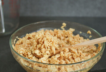 Close up of soy bean meat mince sucked up in water in a glass bowl with a wooden spoon, grey kitchen table