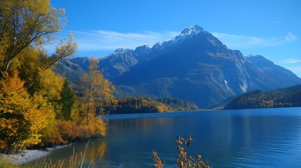 A beautiful mountain range with a lake in the foreground. The lake is calm and the mountains are covered in snow. The scene is serene and peaceful.