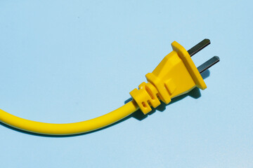 Yellow electric power cable with plug on blue background.