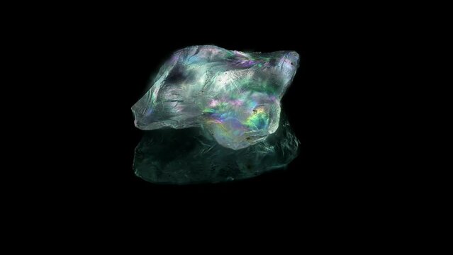 A grain of sand placed on a mirror rotating in polarized light, with shifting birefringent rainbow colors, black background, microscopic, all in focus. Subject is only 0.7mm across.