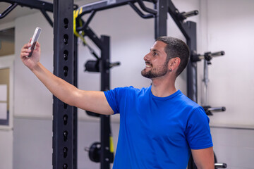 smiling fitness sportsman taking selfie with smartphone during gym workout