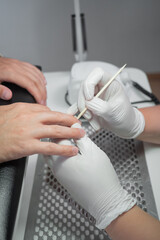 Manicure process for male nails in a beauty salon close up. Professional manicurist in gloves using a wooden stick carefully pushes back the cuticles. Concept spa body care for man