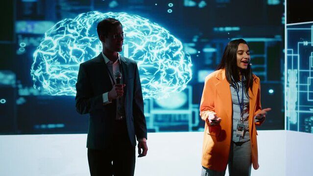 Tech specialists discussing during keynote summit presentation, exploring successful implementation of AI in driving forward businesses, sharing latest artificial intelligence innovations, camera A
