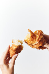 Hands holding bitten croissant on white background