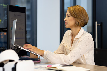 Working on laptop, woman analyzing quarterly report in modern office setting