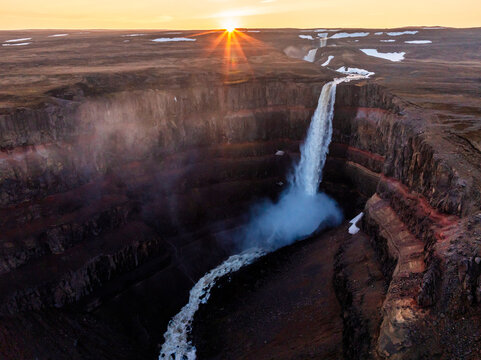 Aerial view on Hengifoss waterfall with red stripes sediments and old soil volcanic formation in Iceland.