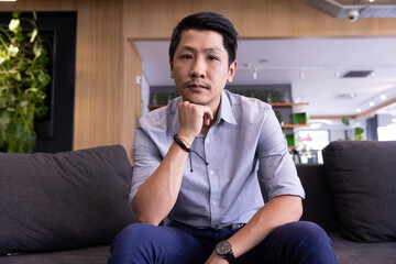 Sitting on couch, man in casual attire looking at camera in modern office