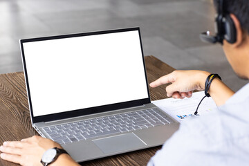 Pointing at blank laptop screen, man wearing headset working from business, copy space