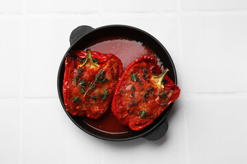 Tasty stuffed peppers in dish on white tiled table, top view