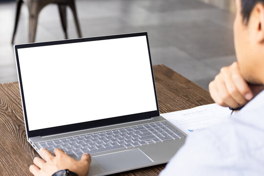 Using laptop with blank screen, man working at desk with document, copy space