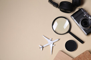 Travel blogger. Flat lay composition with vintage camera and magnifying glass on beige background, space for text