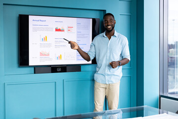 Presenting annual report, man pointing at screen with graphs in modern office