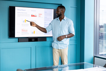 Presenting annual report, man pointing at screen with graphs in modern office