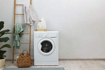 Washing machine, detergents, houseplant and ladder in laundry room, space for text