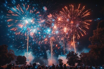 Fireworks are lit up in the night sky above a crowd