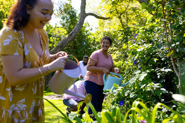 Watering plants in garden, diverse friends enjoying gardening together outdoors