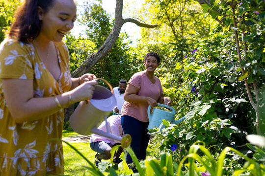 Watering plants in garden, diverse friends enjoying gardening together outdoors