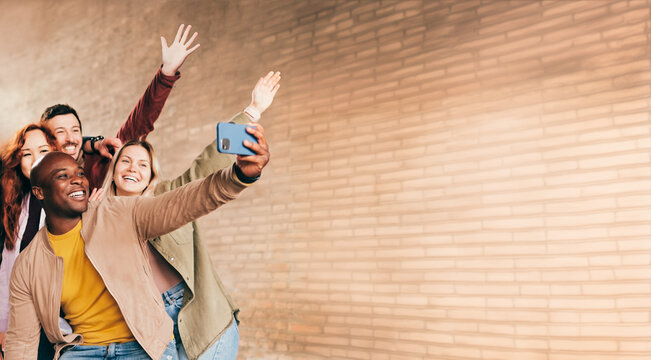 Group of happy friends taking selfie portrait on the city street. Multiracial young people having fun together outside - Friendship concept - Focus on the black man.