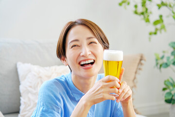 自宅で生ビールを飲む女性