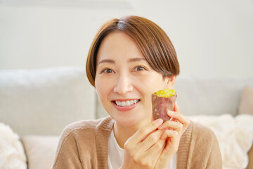 自宅で焼き芋を食べる女性　カメラ目線