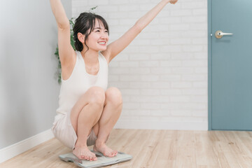 体重計に乗るスリムなアジア人女性(ダイエット・痩身イメージ)
